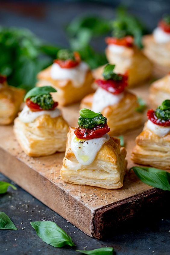 mozzarella tomato and basil on a puff pastry square served on a wood platter