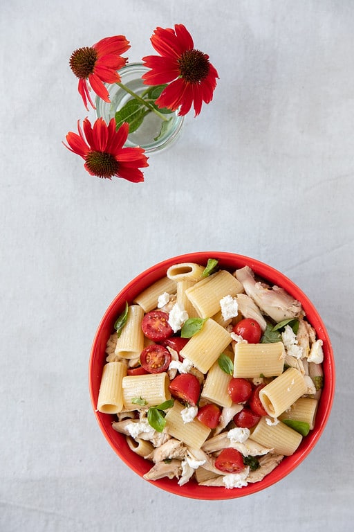 pasta with tomato basil and mozzarella in red bowl