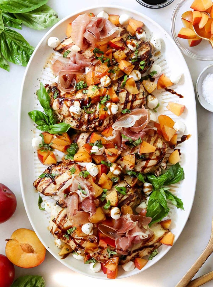 platter with stone fruit, prosciutto, grilled chicken and fresh basil leaves