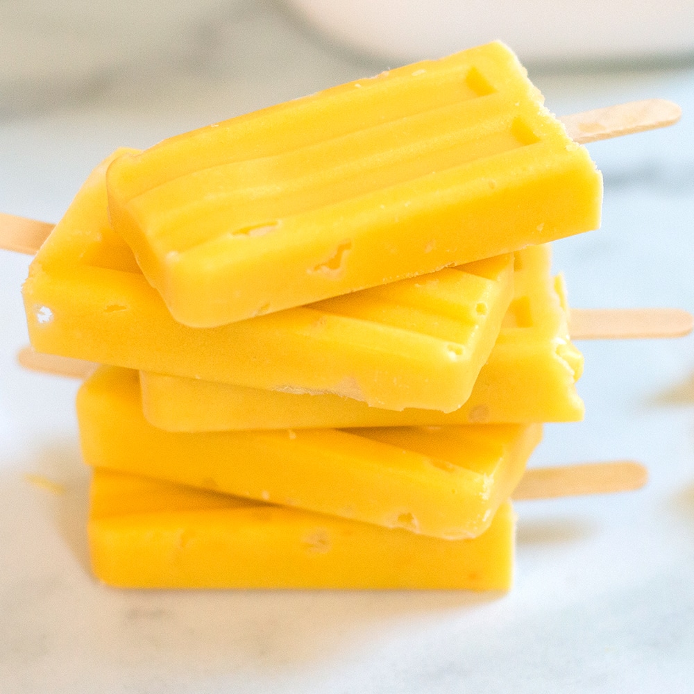 stack of four orange homemade mango popsicle